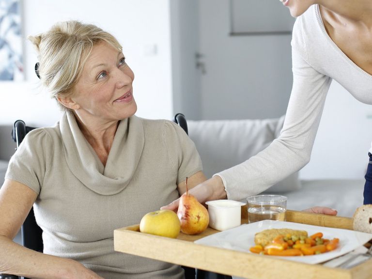 Junge Frau hilft einer Seniorien zu Hause
