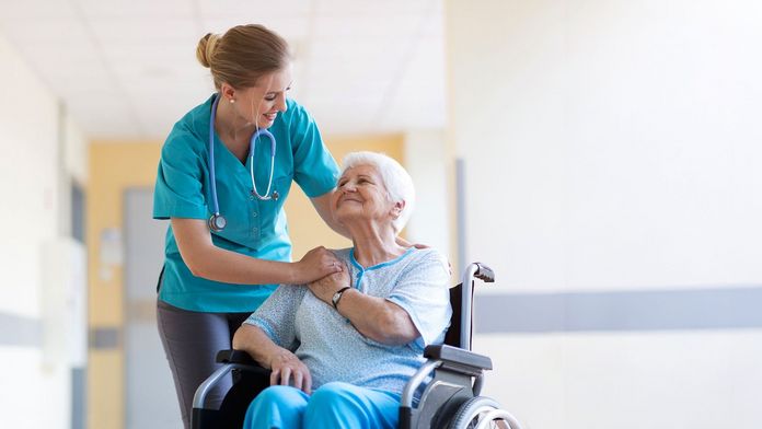 Stationspflegerin betreut eine Pflegebedürftige im Rollstuhl