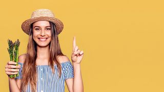 Gesunde Ernährung Frau mit Strohhut hält grünen Spargel in der Hand