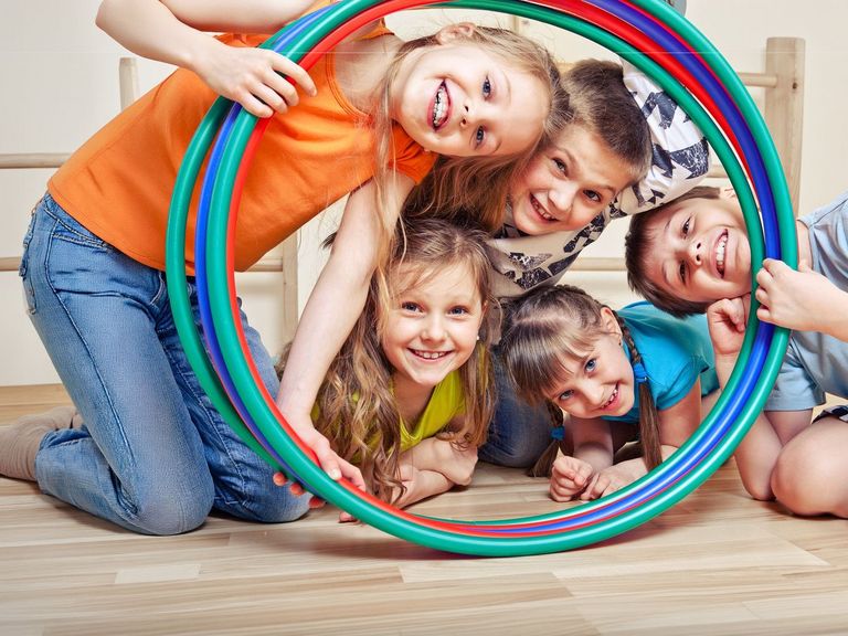 Schüler und Schülerinnen schauen durch Hula-Hoop-Reifen