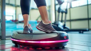 Vibrationsplatten im Sport Sportlerinnenfüße auf einem leuchtenden Vibrationsboard