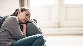 Frau liegt traurig und melancholisch gestimmt auf einer Couch