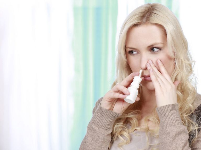 Junge erklältete Frau benutzt Nasenspray