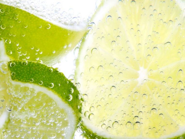 Limettenscheiben schwimmen in sprudelndem Wasser