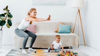 Mutter mit Kleinkind beim eigenen Micro-Workout im Wohnzimmer