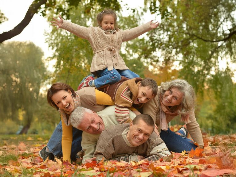 Familie liegt aufeinander gestapelt im Herbstlaub