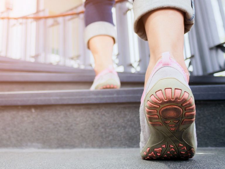 Detailaufnahme von Frauenfüßen in Schuhen, die eine Treppe hoch laufen