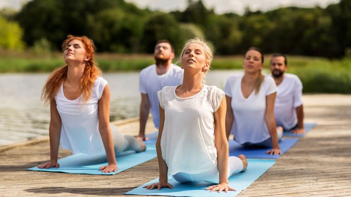 Gruppe Yoga-Sportler auf einem Steg am See