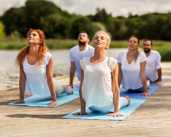Bonusprogramm 2026 Gruppe Yoga-Sportler auf einem Steg am See