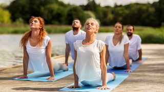 Gruppe Yoga-Sportler auf einem Steg am See
