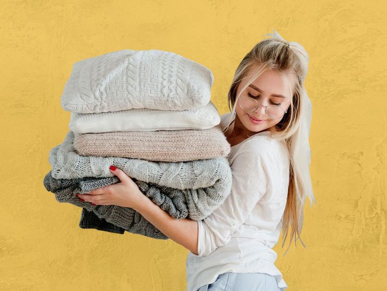 Blonde Jugendliche trägt einen Stapel Kissen