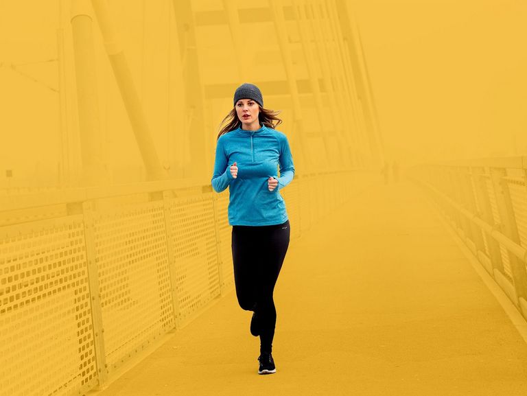 Junge Frau beim winterlichen Joggen über eine Brücke