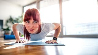 Frau macht im Wohnzimmer Liegestütze als Micro-Workout 