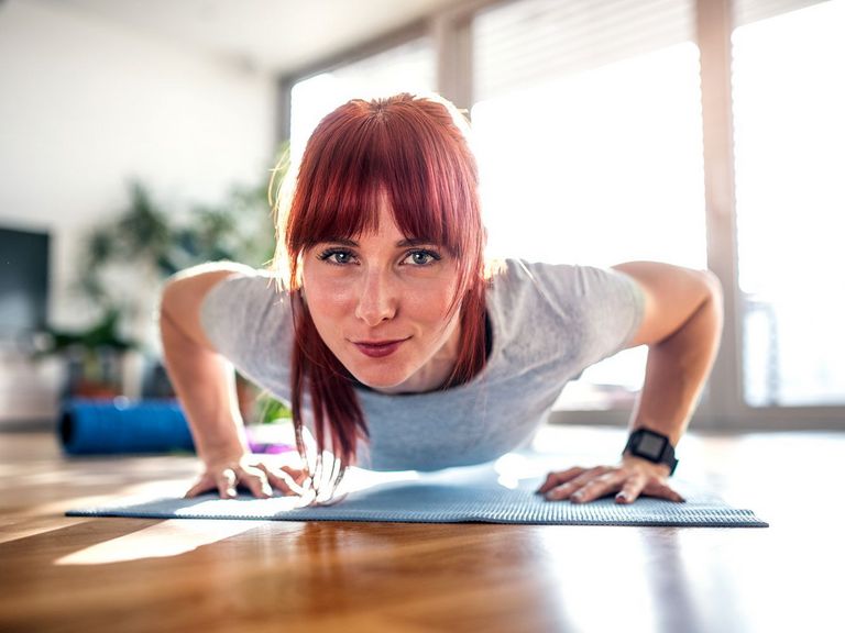 Frau macht im Wohnzimmer Liegestütze als Micro-Workout 