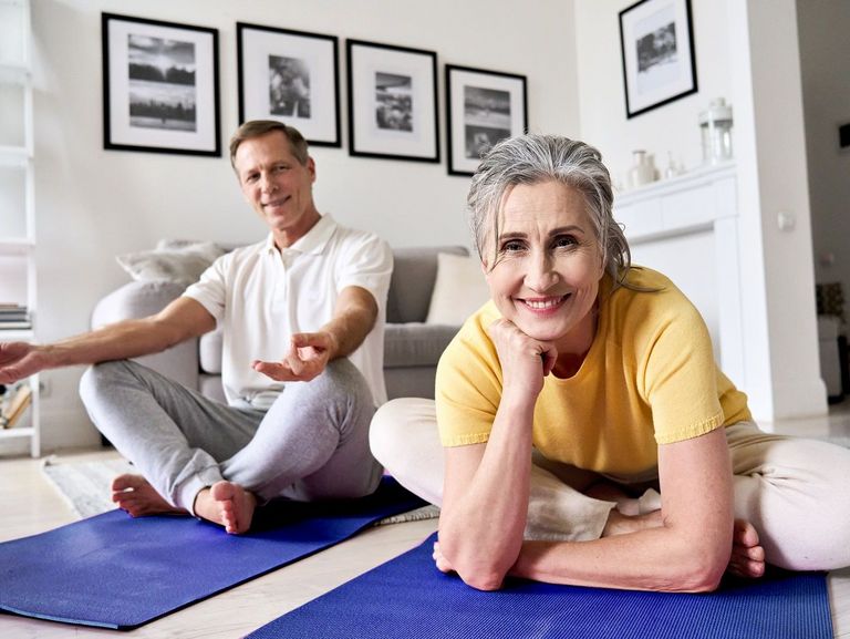 Paar sitzt für eine Meditation im Wohnzimmer auf einer Matte