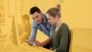 Ausbildungsalltag Junge Frau lässt sich am PC und Tablet etwas erklären