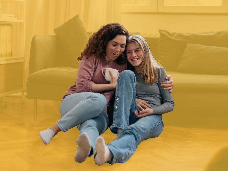 Mutter und Tochter sitzen im Wohnzimmer auf dem Boden