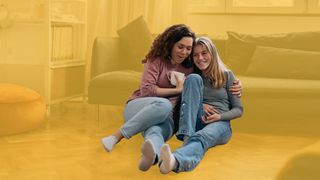 Mutter und Tochter sitzen im Wohnzimmer auf dem Boden