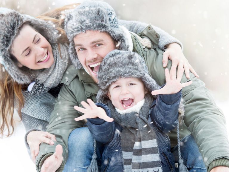 Familie in Winterkleidung lacht in die Kamera