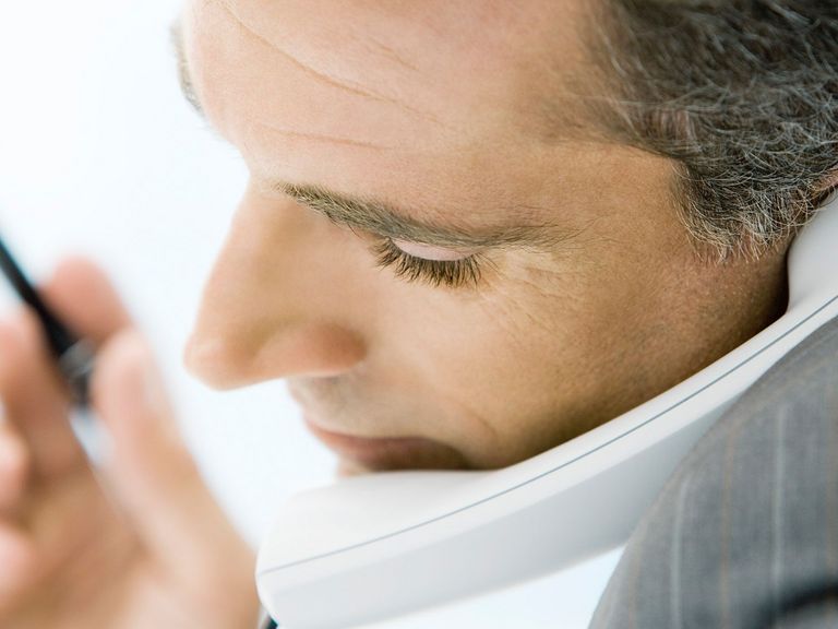 Mann hält Handy zwischen Kinn und Schulter