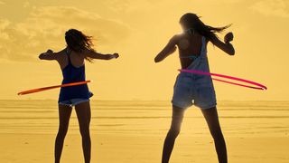 Zwei jungen Frauen am Strand mit ihren Hula-Hoop-Reifen