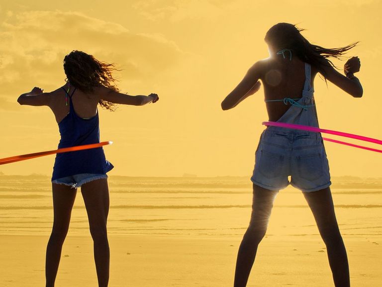 Zwei jungen Frauen am Strand mit ihren Hula-Hoop-Reifen