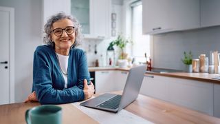 Pflegedienst-Pflegeheim-Suche Älter Frau sitzt in der Küche vor einem Laptop