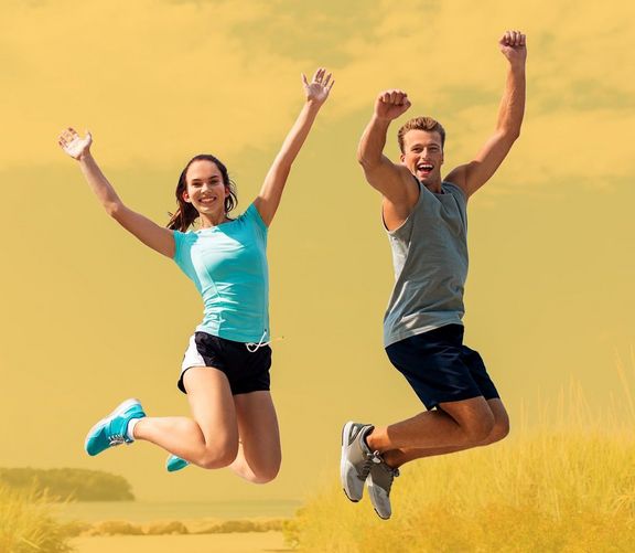 Zwei Jugendliche springen auf einem Strandzugang in die Luft	