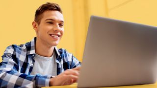 Online-Bewerbung Schulabsolvent vor einem Laptop sitzend