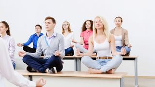 Mind-Factory | Sek II Schüler sitzen auf Schülertischen im Schneidsitz