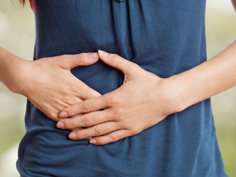 Frau hält sich den Bauch wegen Bauchschmerzen