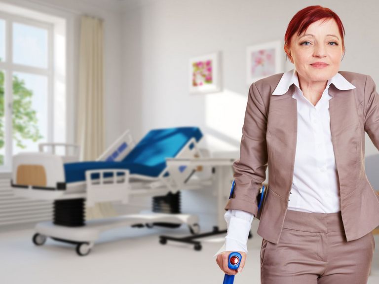 Patientin mit Gehhilfen steht im Patientenzimmer