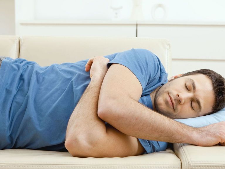 Mann hält auf einer Couch Mittagsschlaf