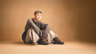 Jugendlicher im Schlabberlook sitzt lässig auf dem Fußboden