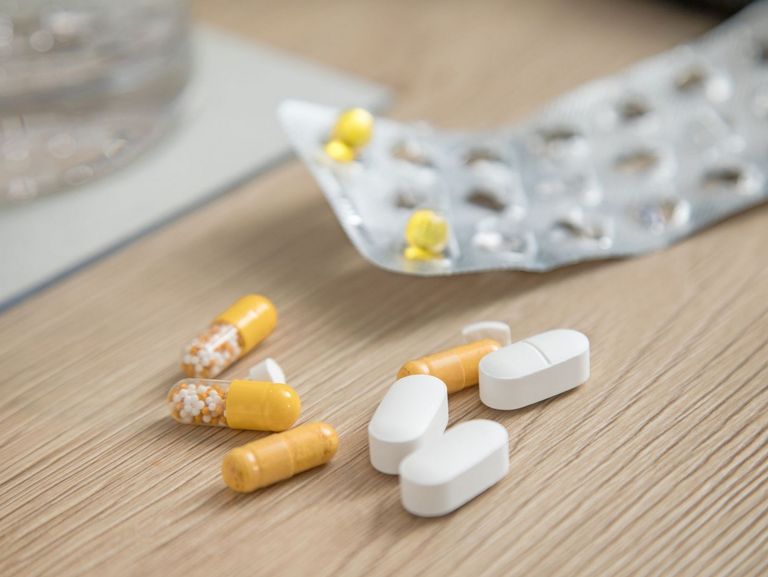 Pillen-Blister mit nur noch sehr wenigen gelben Tabletten und Medikamente auf einem hellen Holztisch