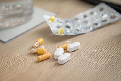 Pillen-Blister mit nur noch sehr wenigen gelben Tabletten und Medikamente auf einem hellen Holztisch