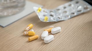 Pillen-Blister mit nur noch sehr wenigen gelben Tabletten und Medikamente auf einem hellen Holztisch