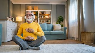 Preventicus Gesundheitscoach Älterer Mann mit Kopfhörern im Schneidersitz und geschlossenen Augen