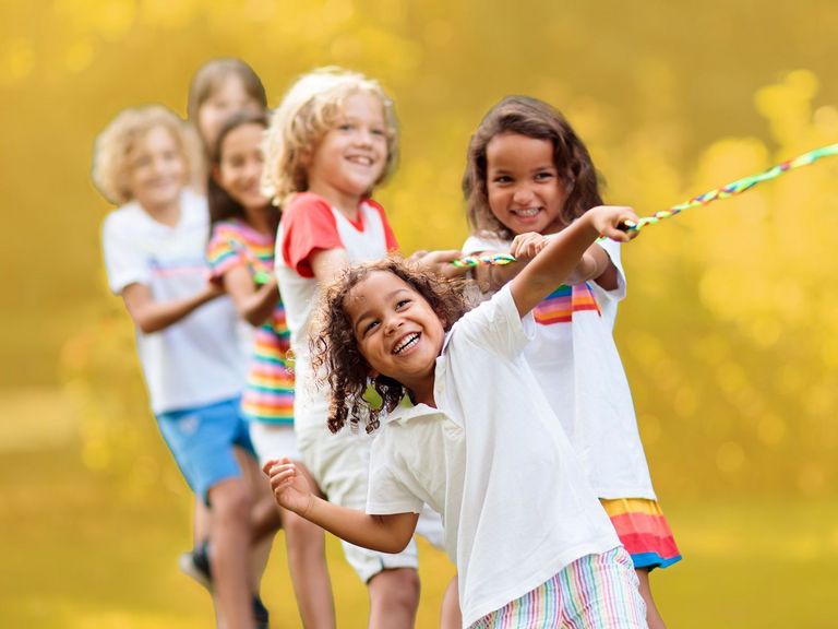 Kleine Gruppe Kinder lacht beim Tauziehen