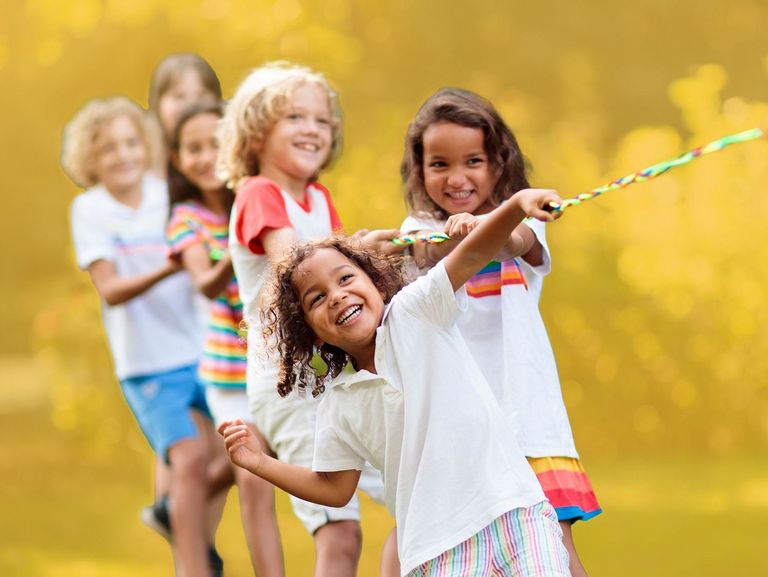 Kleine Gruppe Kinder lacht beim Tauziehen