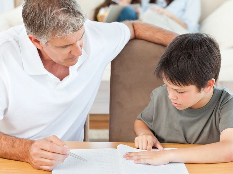 Vater hilft seinem Sohn, sich bei den Hausaufgaben zu konzentrieren