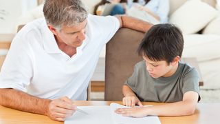Vater hilft seinem Sohn, sich bei den Hausaufgaben zu konzentrieren