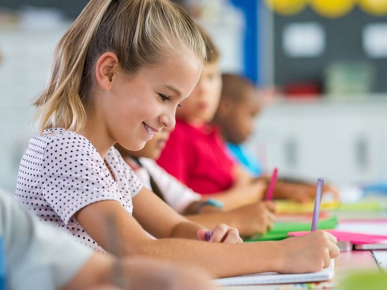 Schüler und Schülerinnen sitzen im Klassenraum und erledigen mit Freude ihre Arbeiten
