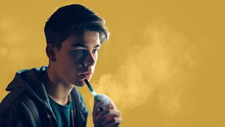 Jugendlicher in einem dunklen Raum nutzt Vaping-Zigarette	