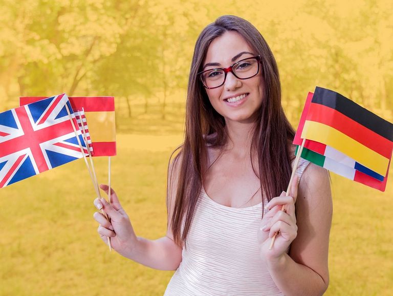 Junge Frau mit Brille hält verschiedenen kleine Flaggen-Fähnchen