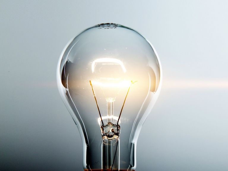 Glimmende Glühlampe vor blau-grauem Hintergrund