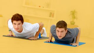 Yoga & Co. Zwei junge Männer machen Übungen auf einer Yoga-Matte