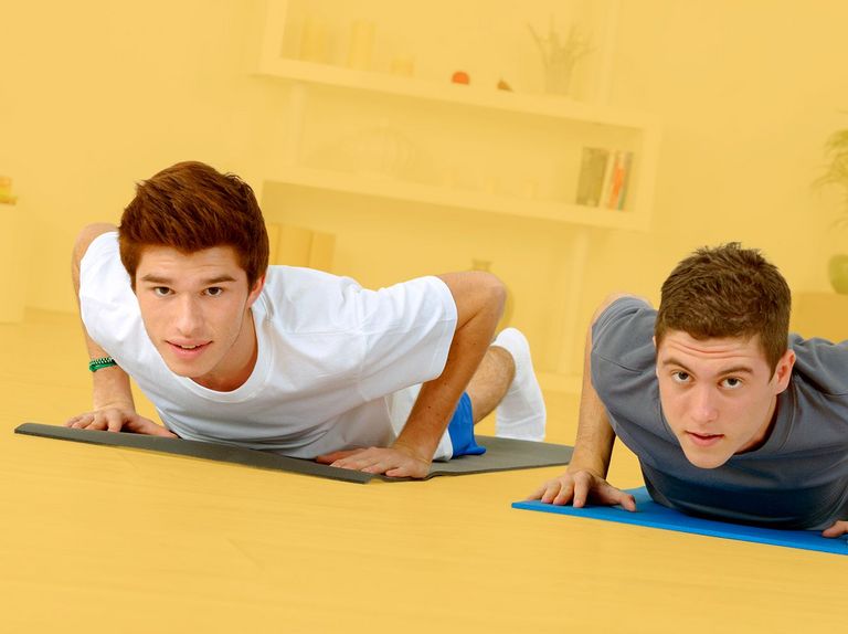 Zwei junge Männer machen Übungen auf einer Yoga-Matte