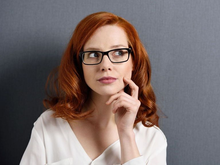 Frau mit überlegender Miene vor grauem Hintergrund