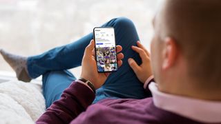 Mann auf einer Couch schaut auf sein Smartphone